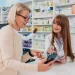 Une femme présente sa carte vitale dématérialisée à la pharmacie